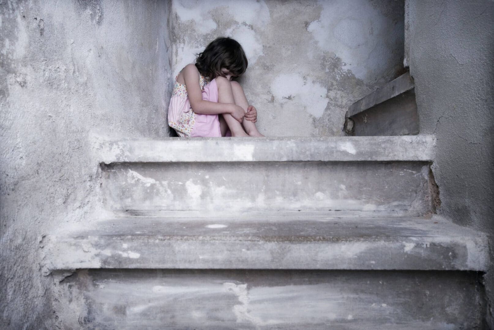 A young girl sitting on the steps of an old building.